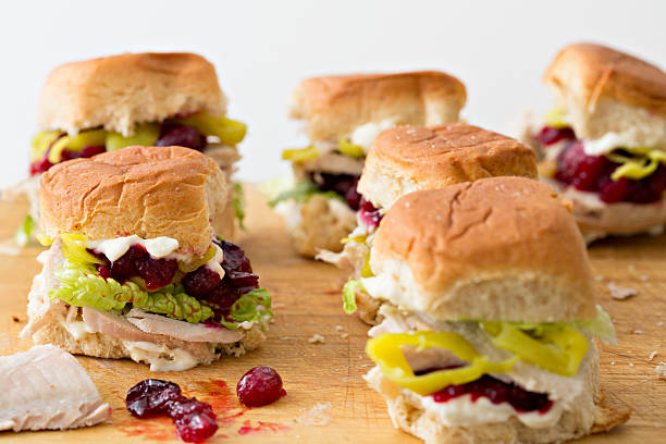 Mini turkey sandwiches with cranberry sauce and lettuce on a wooden board