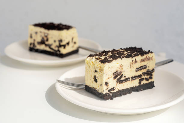 Two slices of Oreo cheesecake served on white plates with forks.