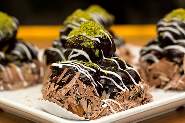 Decadent chocolate desserts topped with green pistachio and white drizzle on a platter.