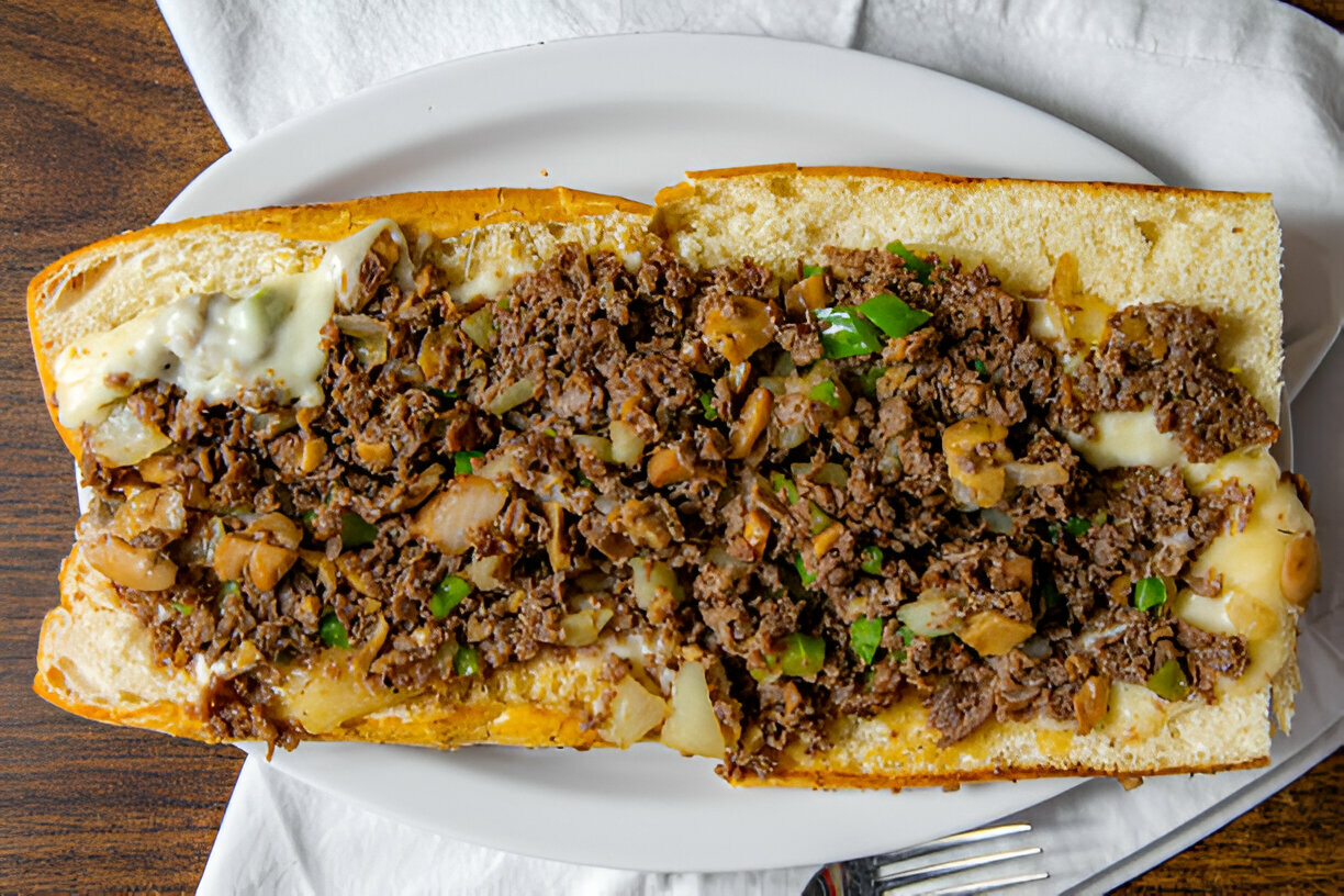 A delicious cheesesteak sandwich filled with seasoned beef, onions, and green peppers on a soft hoagie roll.