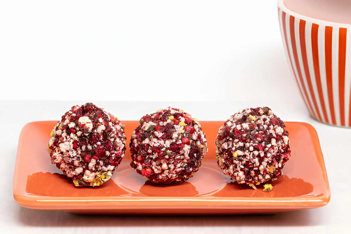 Three colorful dessert balls on a bright orange plate.