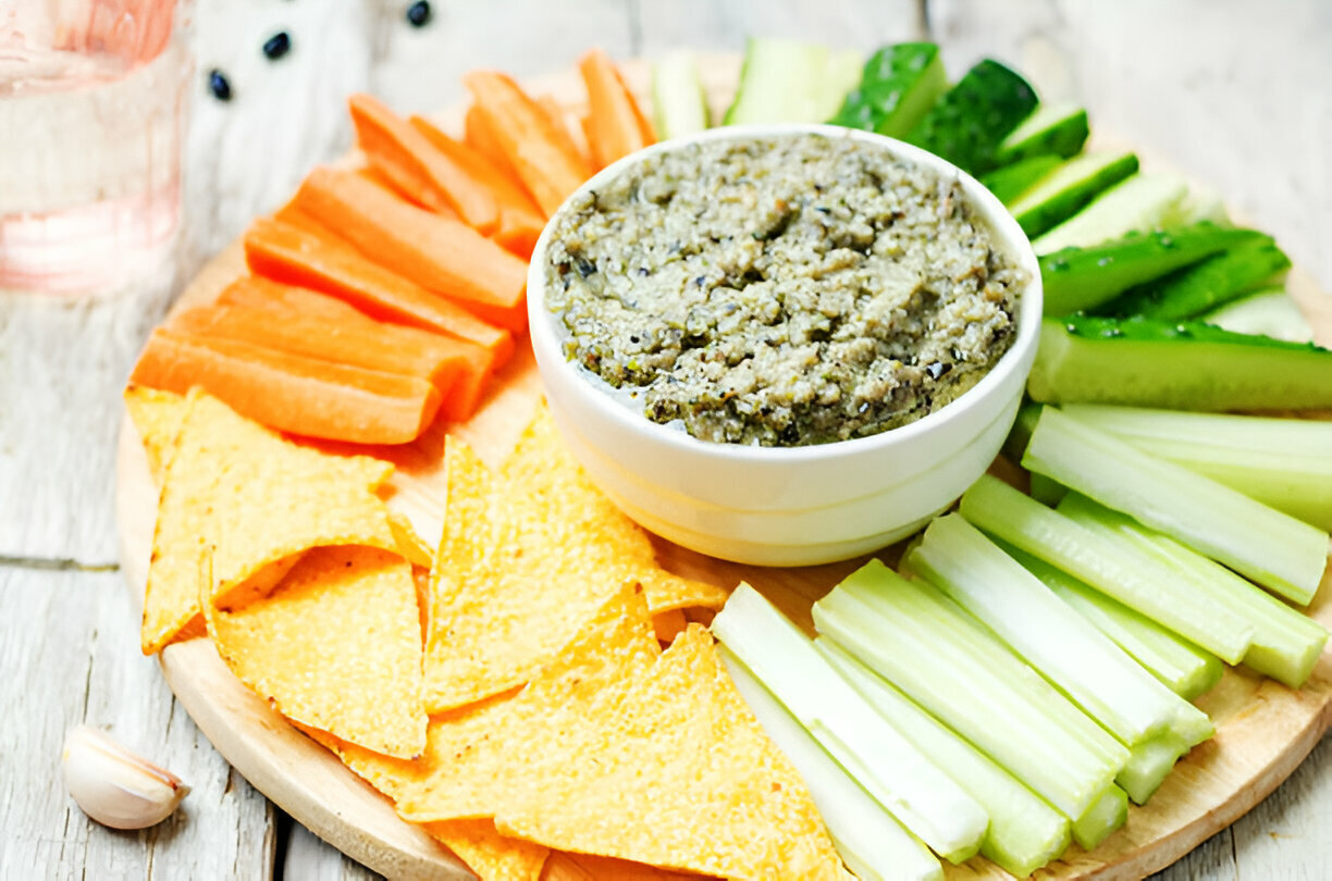 Colorful platter of fresh vegetables and tortilla chips served with a dip.