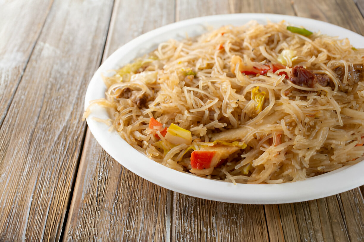 A close-up of a plate of stir-fried noodles with vegetables, served on a white plate.