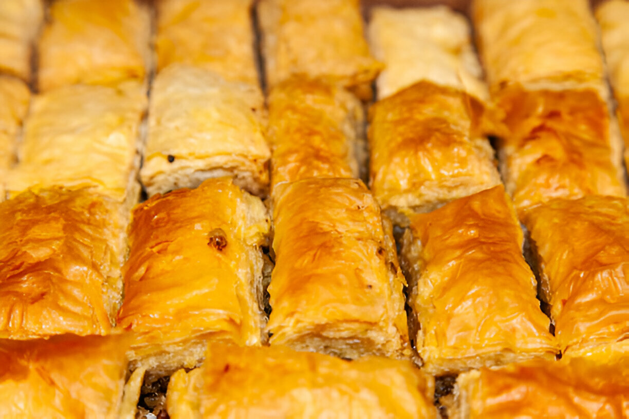 Close-up of golden-brown baklava pieces arranged in a tray.