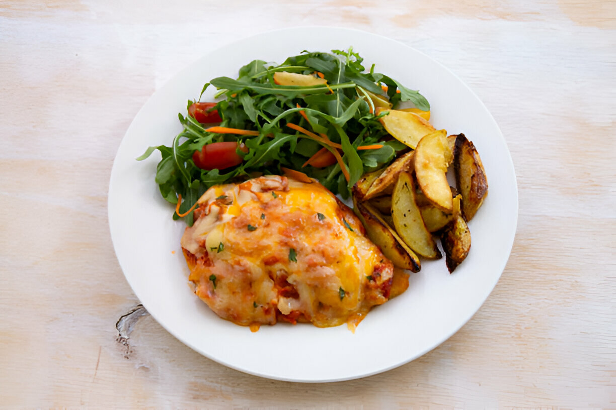 A plate of delicious baked chicken with cheese, accompanied by a side salad and roasted potatoes.