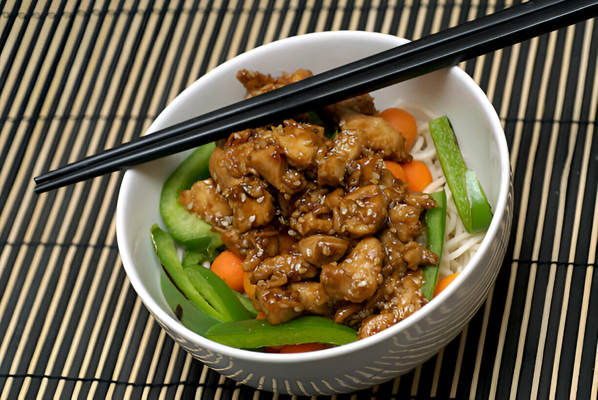 A bowl of chicken stir-fry with vegetables and noodles, garnished with sesame seeds and served with chopsticks.