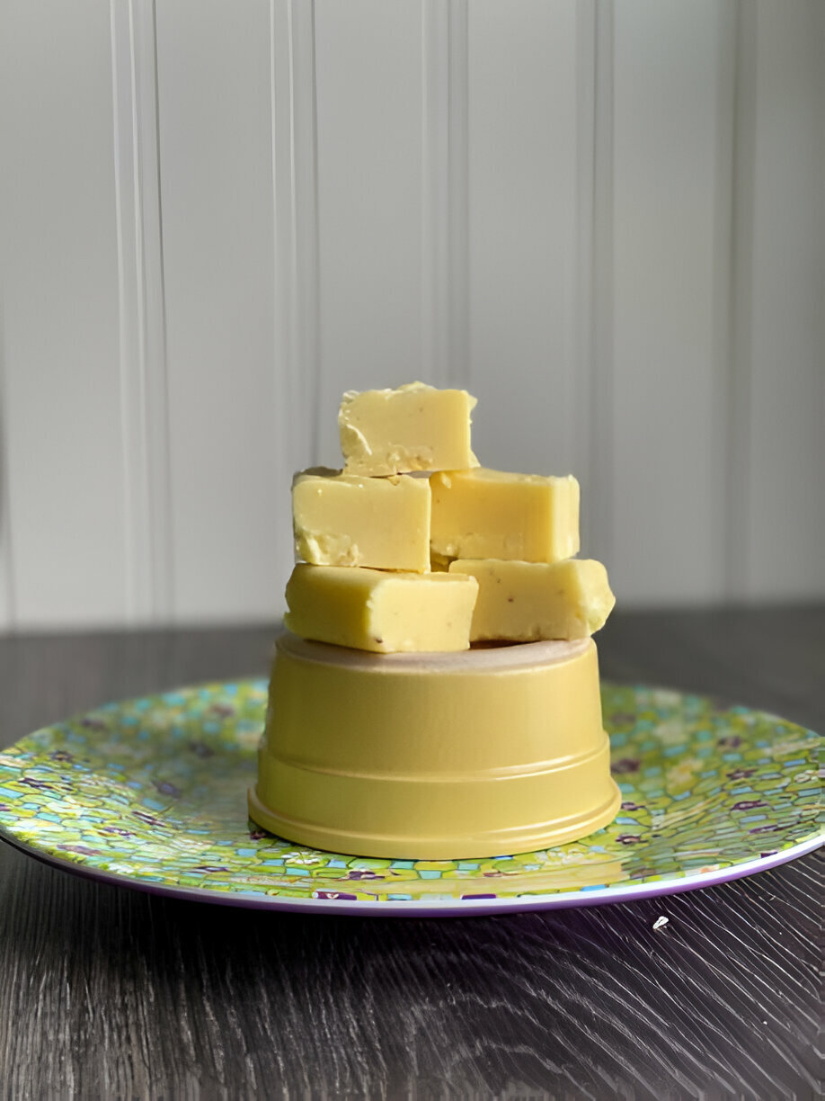 A stack of yellow cheese cubes placed atop a yellow bowl on a colorful plate.