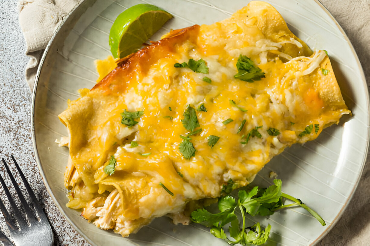 Delicious cheese enchiladas topped with cilantro and a lime wedge on a plate.