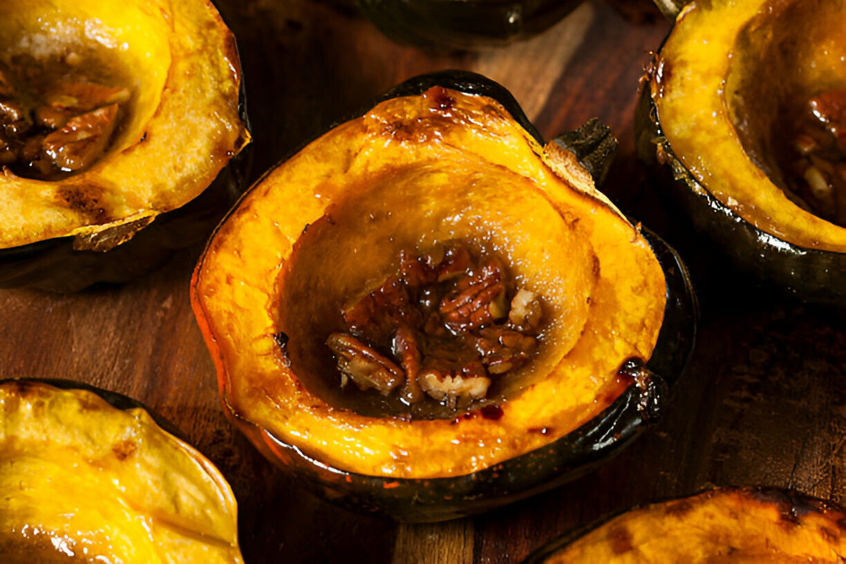 Halved acorn squash with a sweet pecan filling, showcasing a golden yellow interior and dark green outer skin.