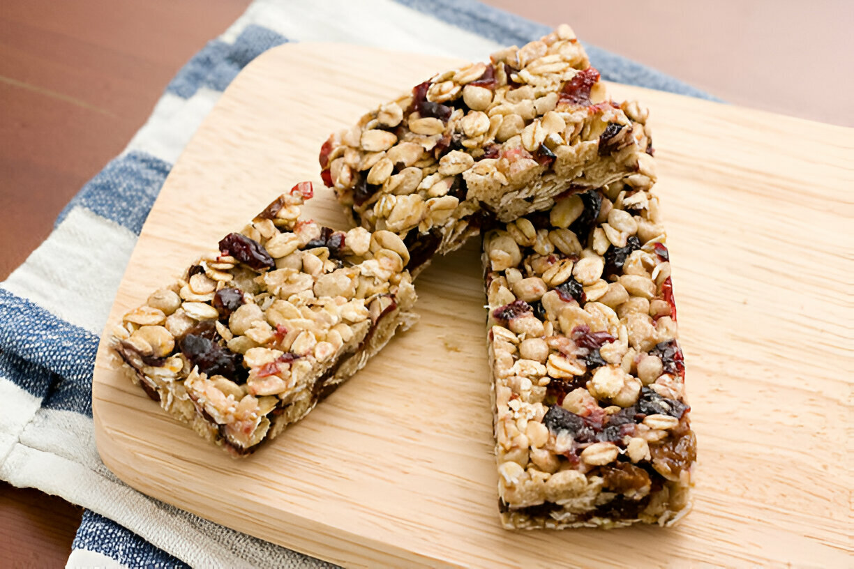 Homemade granola bars with oats and dried fruit on a wooden cutting board.