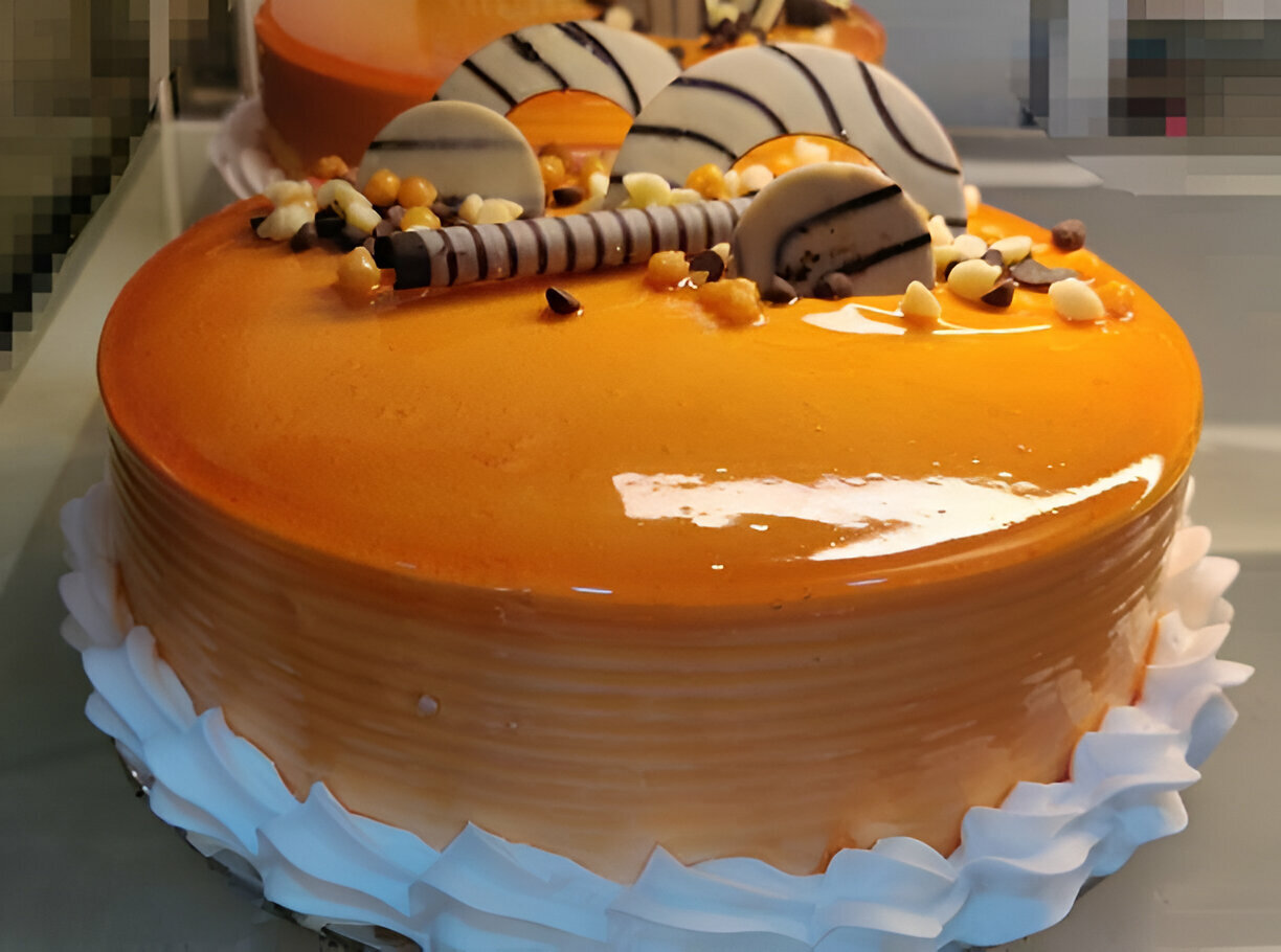 A beautifully decorated orange cake with white icing and chocolate decorations.