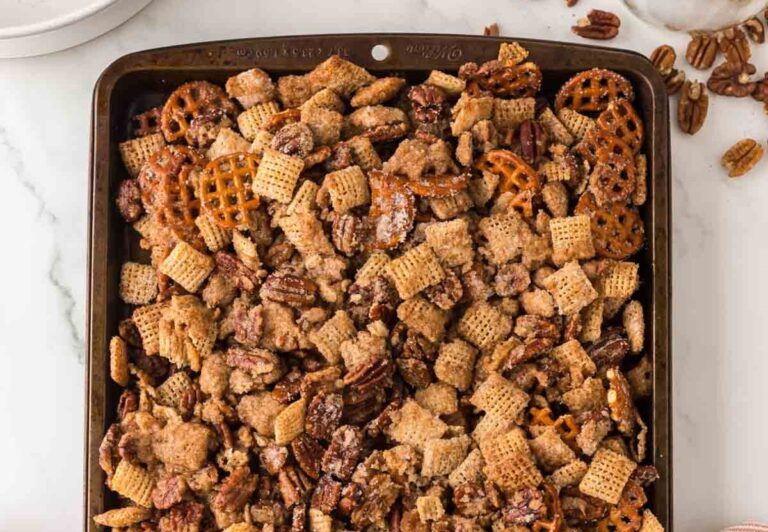 A tray filled with a mix of Chex cereal, pretzels, and pecans, coated with a sweet and crunchy coating.