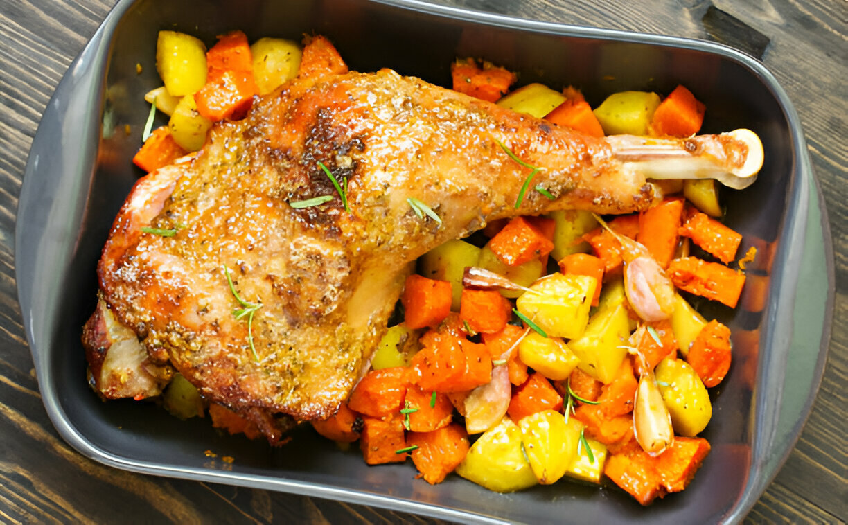 A roasted turkey leg served with colorful roasted vegetables including carrots and potatoes.