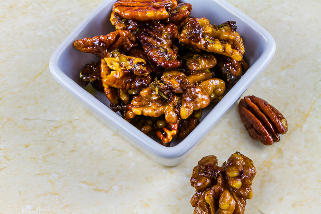 A bowl of caramelized pecans on a light background.