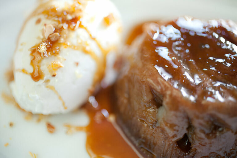 A plate featuring a creamy scoop of vanilla ice cream drizzled with caramel sauce beside a moist dessert.