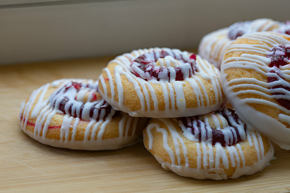 A close-up of freshly baked pastries with a glossy icing and fruit filling.