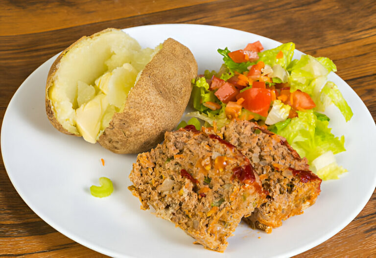 A plate featuring a baked potato with butter, a serving of meatloaf drizzled with ketchup, and a fresh salad with tomatoes and lettuce.